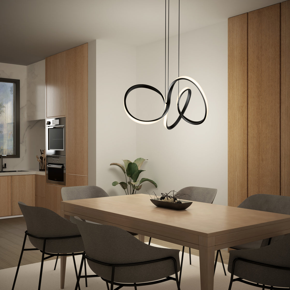 A modern dining room with a light wooden table, six gray upholstered chairs, minimalist wood cabinetry, a built-in oven, a corner plant, and the Swirl LED pendant light by Artika hanging above the table.