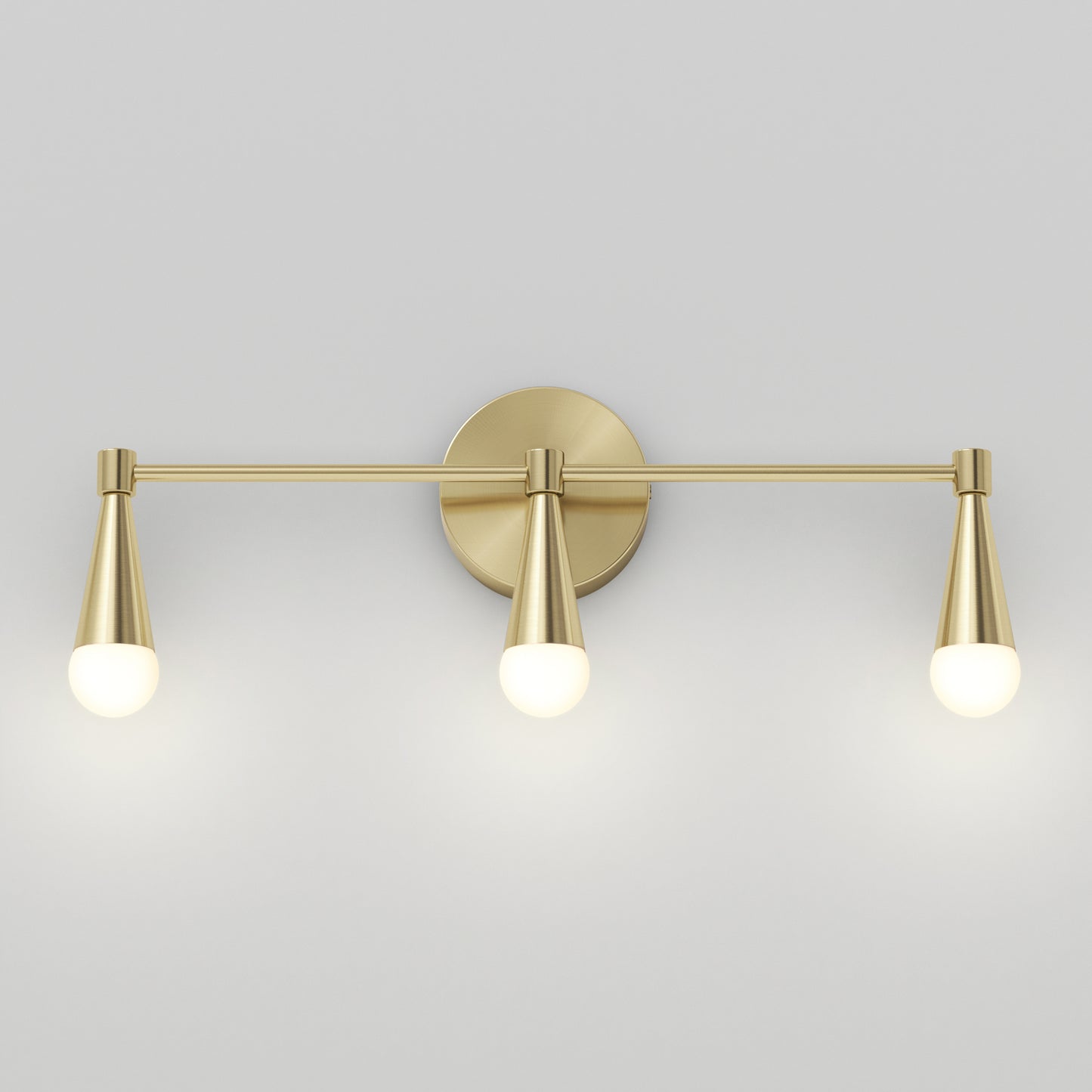 The Artika Wayden LED mid-century bathroom vanity light 3 CCT features three brass cone-shaped arms with round white bulbs, mounted on a circular backplate and displayed against a plain light gray wall.