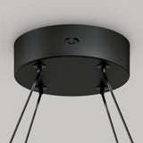 Close-up view of a black, round ceiling mount with four cables extending downward, attached to the bottom surface, likely part of a modern hanging light fixture.