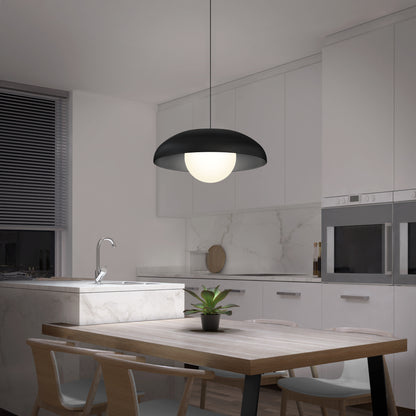 A modern kitchen features white cabinets, a marble backsplash, a built-in oven, and a wooden dining table with four chairs. A potted plant sits on the table beneath the Artika Boden LED modern mid-century pendant light (3 CCT).