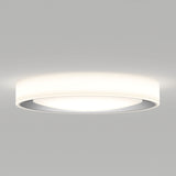 A modern, round, white ceiling light fixture with a sleek, minimal design, emitting a soft, diffused glow against a plain light gray ceiling.