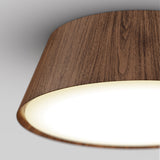 A close-up view of a ceiling lamp with a wooden finish and a glowing white light, mounted on a white ceiling.