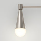 A modern wall sconce with a brushed metal conical fixture and a round white frosted bulb, mounted on a horizontal metal rod against a light gray background.