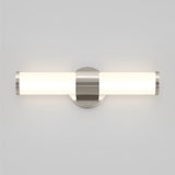 A modern wall-mounted light fixture with a cylindrical frosted glass shade and metallic accents, emitting a soft, even glow against a plain light gray wall.