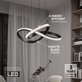 The Artika Morgan LED contemporary pendant light with intertwined matte black loops and 5 CCT settings hangs stylishly in a living room. Features energy efficiency, integrated LED, 3-year warranty; shelves, chair, and vase in background.
