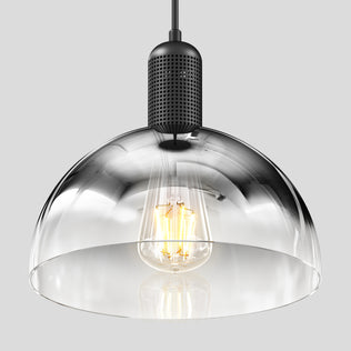 The Artika Nella Pendant without Bulbs features a clear glass shade and black perforated metal fixture, showcasing a visible filament bulb, all set against a plain gray background.