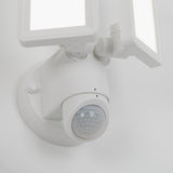 A close-up view of a white outdoor motion sensor light with two rectangular LED panels and a round motion detector on a wall.