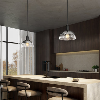 A modern kitchen with a large island, four cushioned bar stools, dark wood cabinets, Artika’s Nella Pendant without Bulbs, and a window with sheer curtains letting in natural light.
