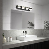 A modern bathroom with a rectangular mirror, wall-mounted black faucet, white square sink, and four globe lights above. Decorative items and greenery sit on a gray countertop with a tiled backsplash.