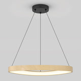 A modern circular pendant light with a wooden frame, suspended by three thin black cables from a black ceiling mount, glowing with soft white light against a plain gray background.