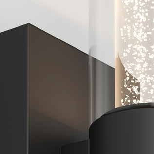 Close-up of Artika's Essence 1-light LED bathroom vanity light featuring a black finish and a cylindrical bubble glass cover.