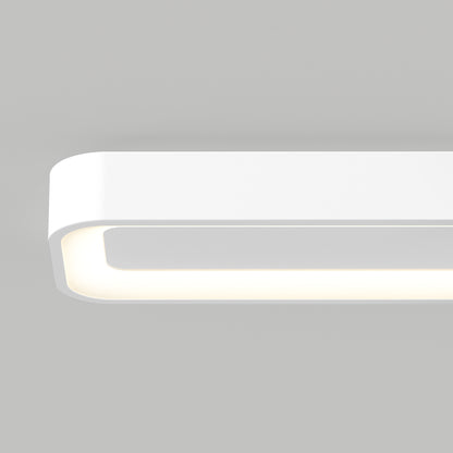 The Artika Aiden 48 in. LED modern flush mount light 5 CCT, with a sleek rectangular design and rounded corners, is mounted on a light gray wall and emits a soft, even glow from its underside.