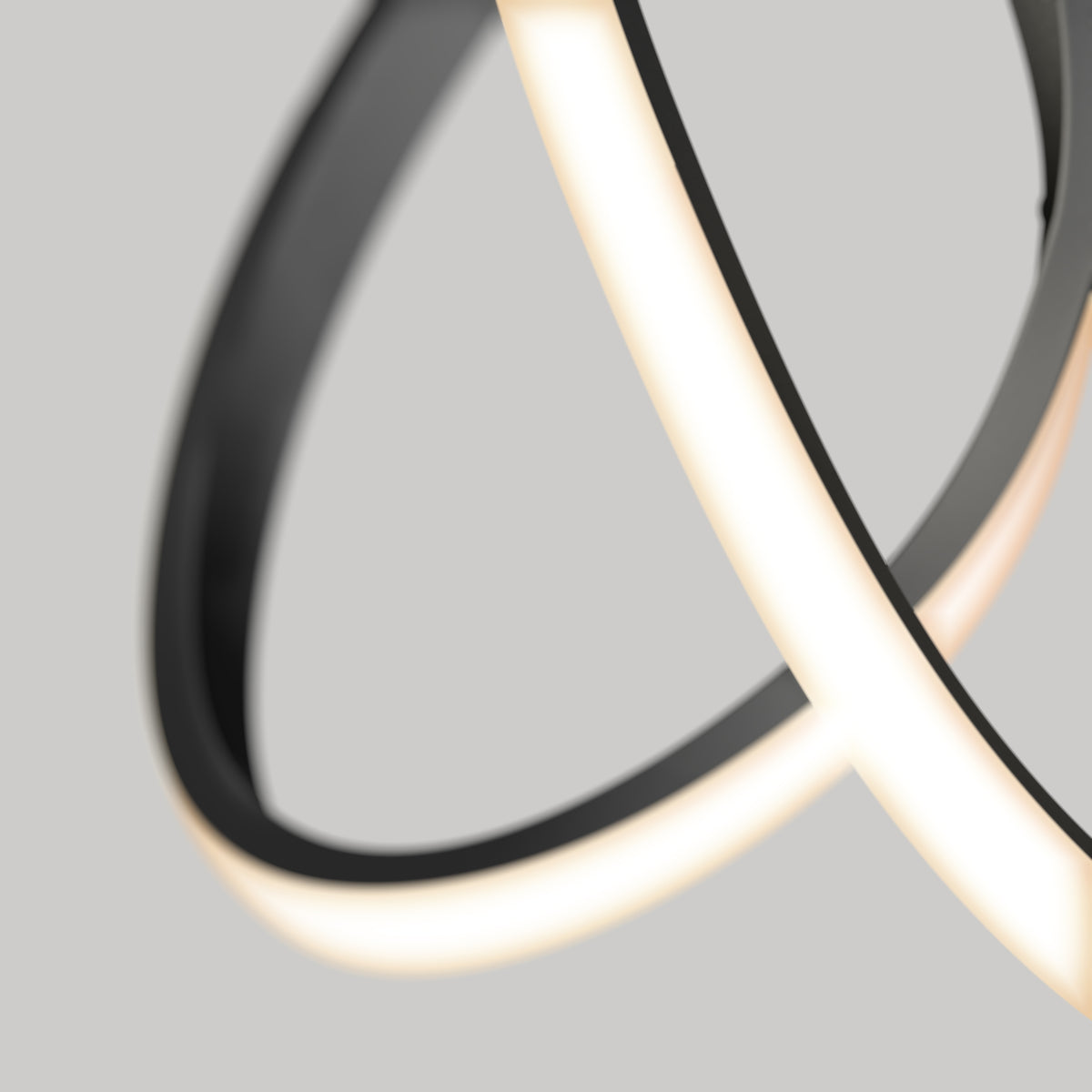 Close-up of a modern, abstract LED light fixture with curved, overlapping black and white luminous bands against a plain grey background.