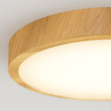 Close-up of a round ceiling light fixture with a wooden frame and a soft, white glowing surface, mounted on a white ceiling.