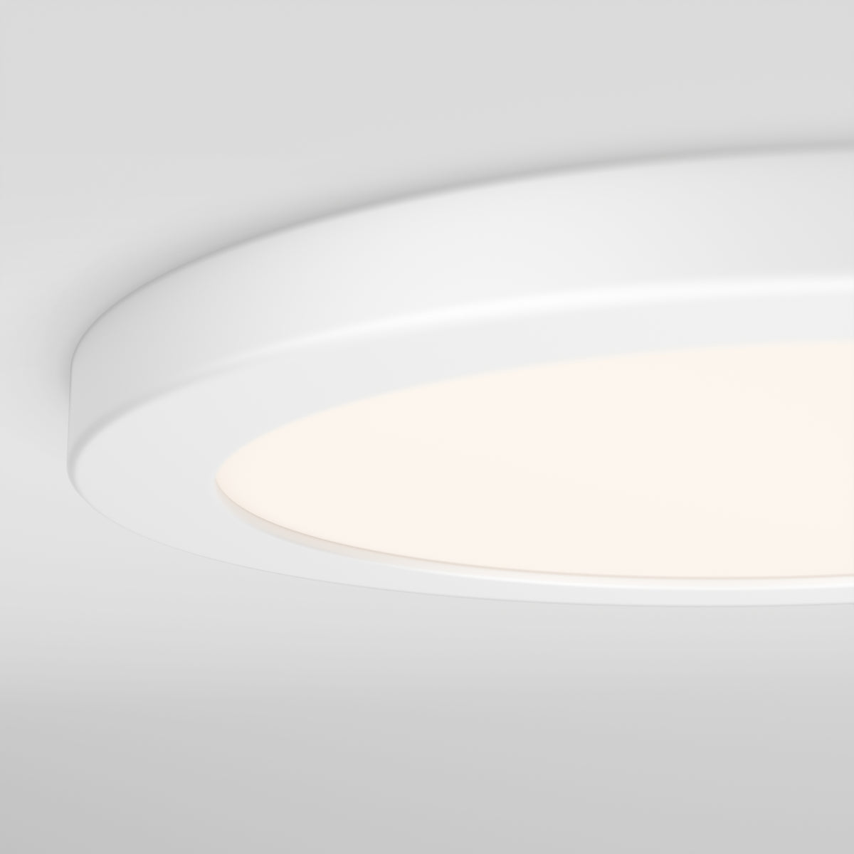 A close-up view of a modern, round, white ceiling light fixture with a soft glow, mounted on a smooth white ceiling.
