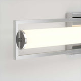 A modern wall-mounted light fixture with a rectangular metal frame and a cylindrical frosted glass shade, emitting a soft, warm glow against a light-colored wall.
