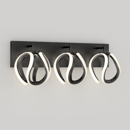 The Artika Vivaldi LED contemporary bathroom vanity light features three abstract looped fixtures with integrated LEDs, all mounted on a rectangular black base, shown here against a light gray background.