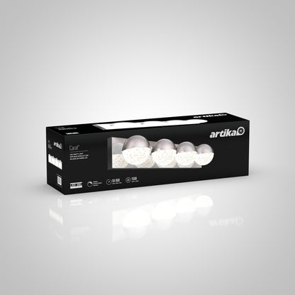 A rectangular black box labeled Artika displays the Carat LED bathroom vanity light, with a clear window revealing the fixture inside the packaging.