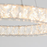 Close-up of a modern circular chandelier with sparkling crystal accents, emitting a bright, shimmering light against a neutral background.