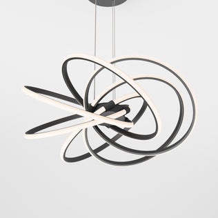 The Artika Maelstrom LED pendant light features multiple intertwined black and white LED rings suspended by thin cords, creating a modern statement against a plain white background.