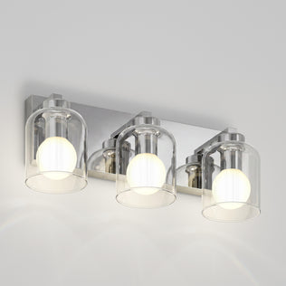Artika Aryna 20 in. (51 cm) 3-Light LED Wall Vanity 3000K with three glass bell shades and glowing bulbs on a rectangular chrome base.