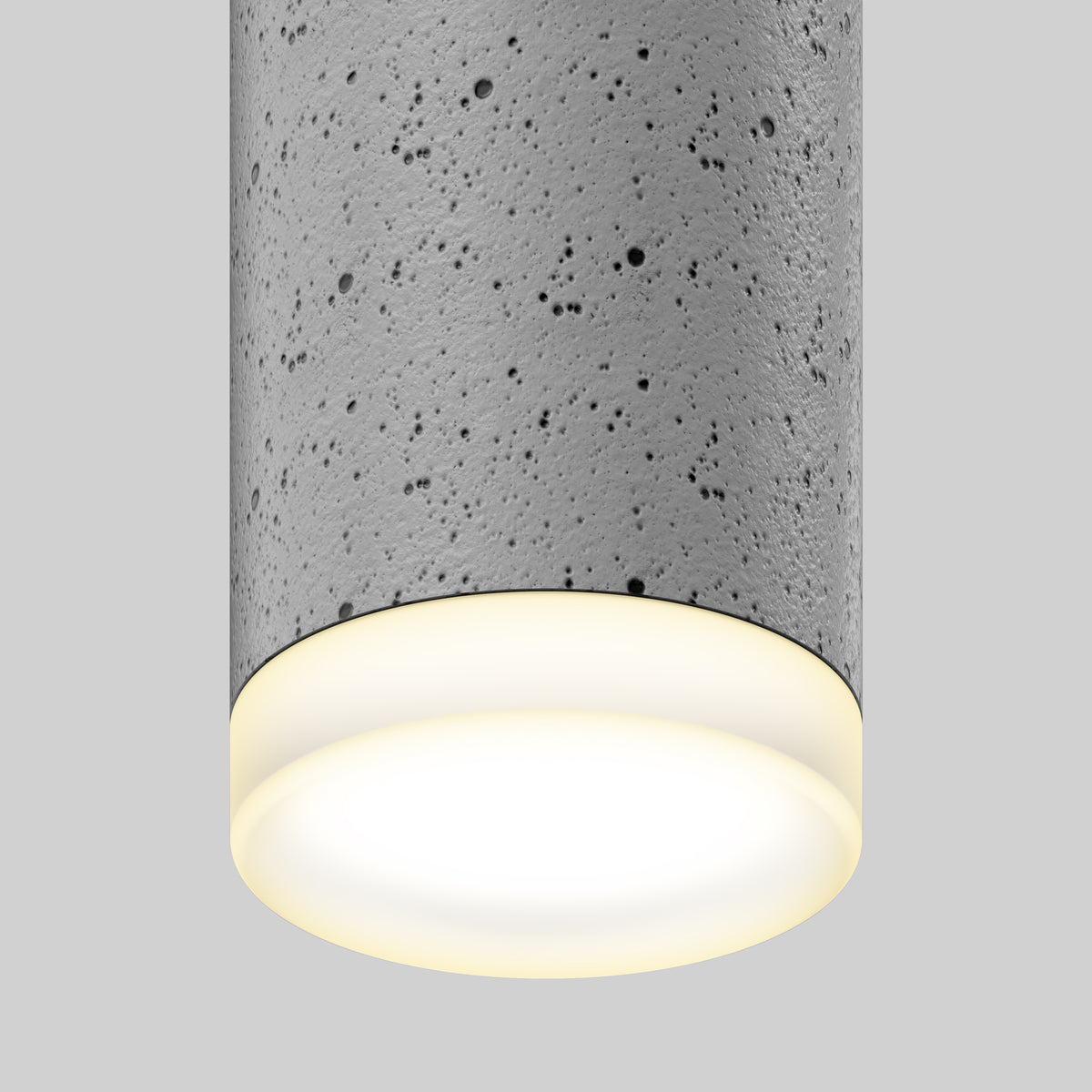 A close-up of a cylindrical ceiling light fixture with a gray, speckled, concrete-like texture and a softly glowing white light against a plain light gray background.