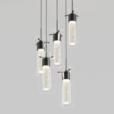 Six modern cylindrical pendant lights with clear outer glass and illuminated inner tubes hang at varying heights against a plain light gray background.