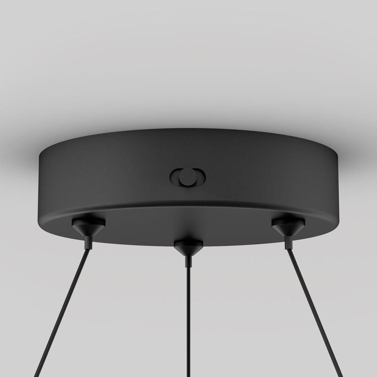 A black, round ceiling light canopy with three cords extending downward, mounted against a white ceiling. The design is modern and minimalistic.
