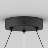 A black, round ceiling light canopy with three cords extending downward, mounted against a white ceiling. The design is modern and minimalistic.