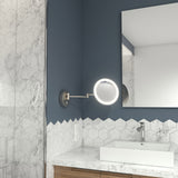 Modern bathroom with a blue and white hexagonal tile wall, a round illuminated wall-mounted mirror, a square sink with a chrome faucet, and a wooden vanity below. A large mirror is visible on the right.