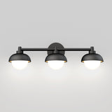 A modern black wall-mounted light fixture with three dome-shaped lamps, each glowing softly against a light gray background.
