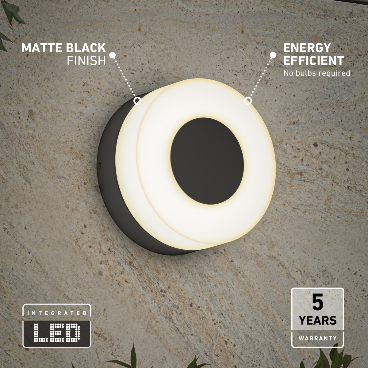 Modern round wall light with a matte black finish mounted on a textured wall. It is glowing softly, labeled energy efficient and integrated LED. Icons highlight 5 years warranty and no bulbs required. Some green plants are visible below.