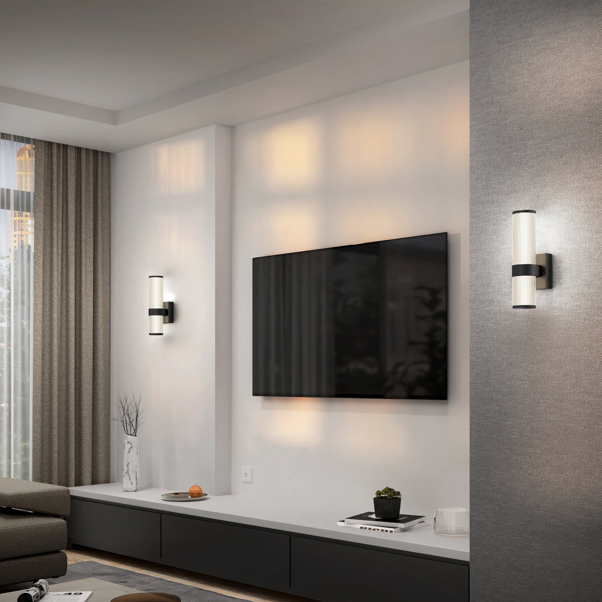 Modern living room with a wall-mounted flat-screen TV, two cylindrical wall sconces, a gray sofa, floor-to-ceiling curtains, and a minimalist cabinet with decorative vases and branches.