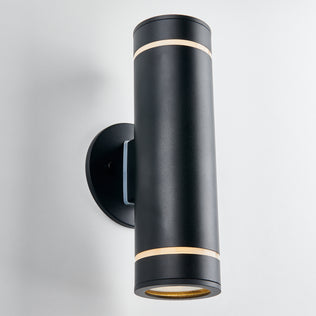 The Artika C7 indoor-outdoor wall light is a modern black cylindrical sconce with gold accents, rustproof, mounted vertically on a round base, and designed to cast light up and down for versatile lighting needs.
