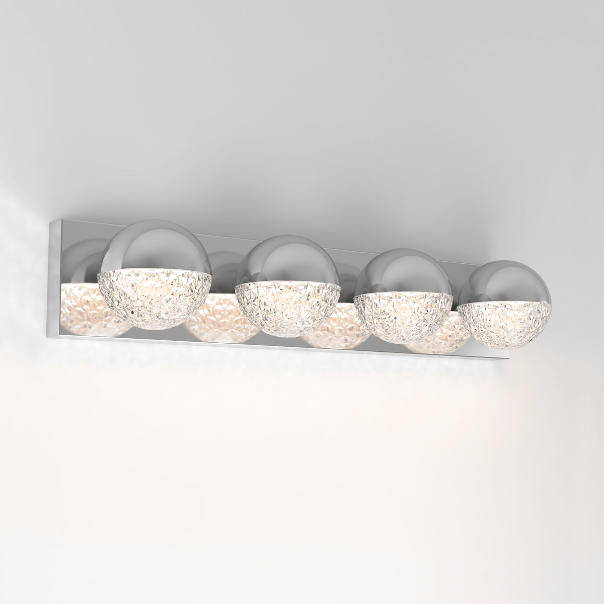 The Artika Carat 27-in (69 cm) Integrated LED Vanity Light Bar features four chrome and textured translucent spheres, casting soft, warm light against a white wall—a modern choice for bathroom lighting.