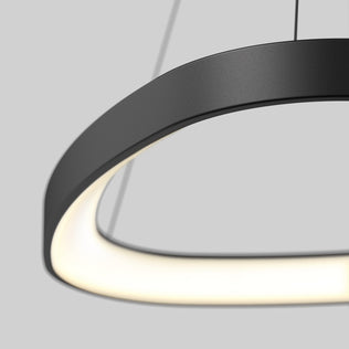 A close-up of the Artika Bjorn modern LED pendant light 5 CCT, featuring a circular black design with a smooth, glowing inner edge, suspended by thin cables against a plain grey background.