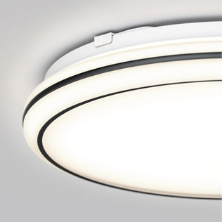 Close-up of the Artika Emina 13 in. LED flush mount light 3 CCT, featuring a modern white and black design and dimmable, even illumination against a light gray ceiling.