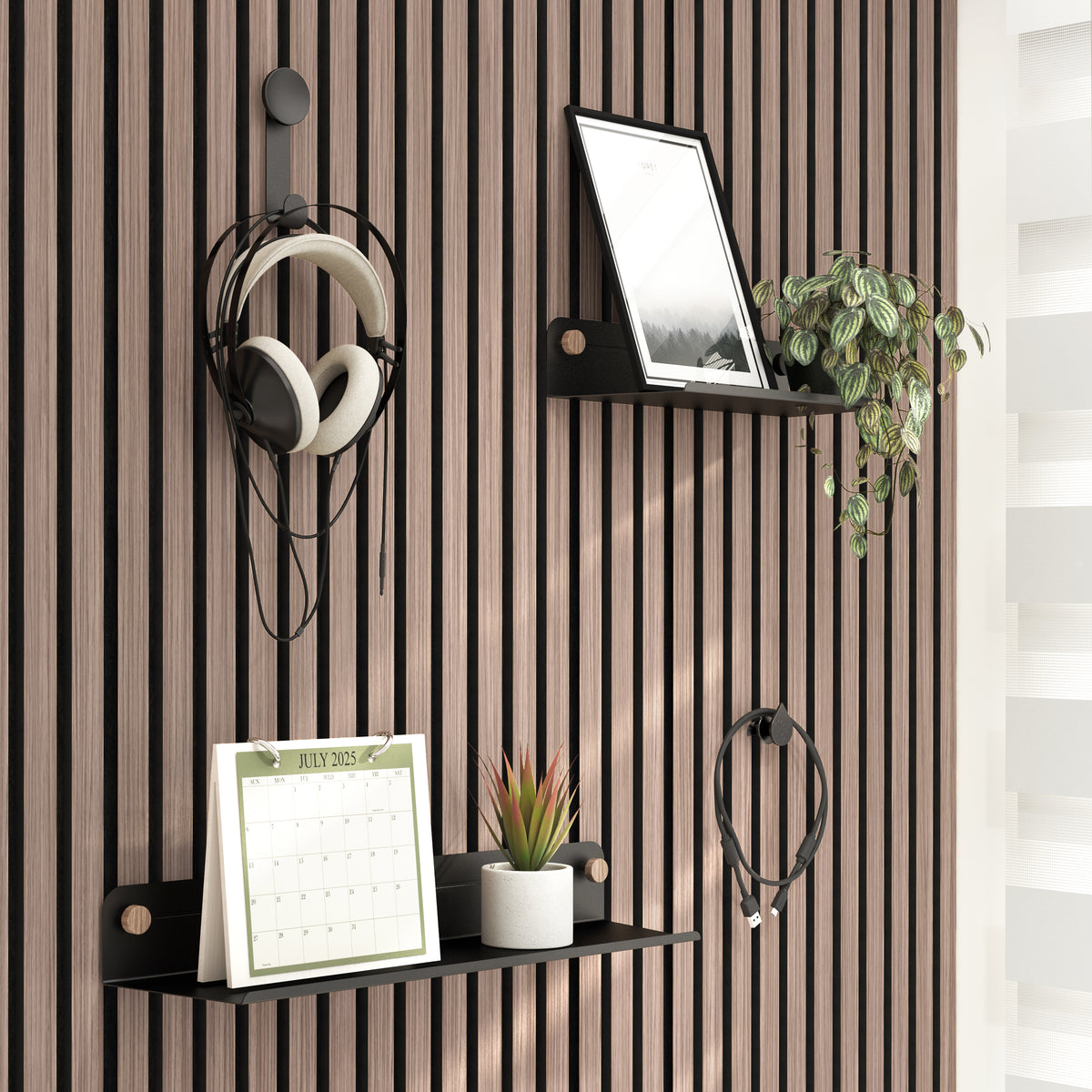 The Artika Sonokit set of shelves and hooks for Sonolok and Sonofold wall panels displays a framed photo, potted plant, July 2023 calendar, small succulent, and headphones on a modern slatted wall with sunlight from the right.
