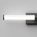 A modern, horizontal wall-mounted LED light fixture with a cylindrical white diffuser and dark end caps, attached to a rectangular dark base against a plain gray wall.