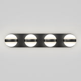 A modern wall light fixture with four evenly spaced circular lights, each partially covered by a horizontal black bar, mounted on a rectangular black base against a plain gray background.