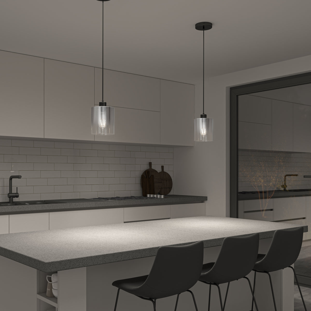 A modern kitchen with a gray island, three black chairs, white cabinets, subway tile backsplash, and two pendant lights hanging above the countertop. A black faucet and two cutting boards are visible near the sink.