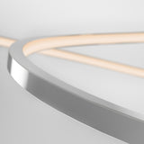 Minimalist close-up of a modern, curved metallic and light fixture against a white background, featuring sleek lines and soft, glowing illumination.
