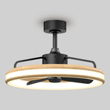 A modern ceiling fan with a circular wooden frame, integrated LED light ring, and a black metal fixture, mounted on a gray ceiling. The fan has three black blades enclosed within the light ring.
