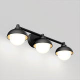 A modern wall light fixture with three round, frosted glass bulbs and black metal shades mounted on a horizontal bar against a light gray background.