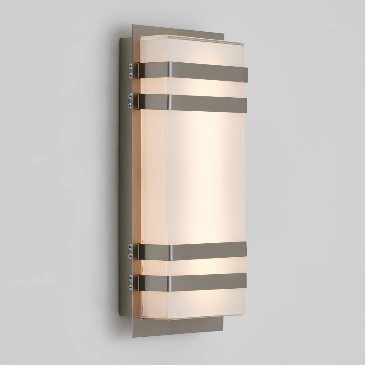 A modern wall sconce light featuring a rectangular frosted glass shade with three horizontal metal bands and a metallic backplate, mounted on a light gray wall.