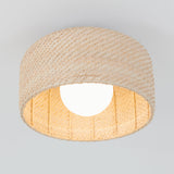 A ceiling light fixture with a round, woven rattan shade and a glowing bulb in the center, mounted on a white ceiling.