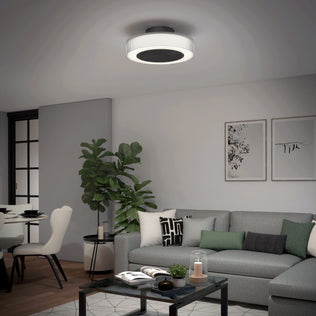 Modern living room with a gray sofa, monochrome pillows, potted plant, abstract wall art, round coffee table, and the Artika Groove 20 in. LED modern ceiling fan (3 speeds) with remote for soft illumination.