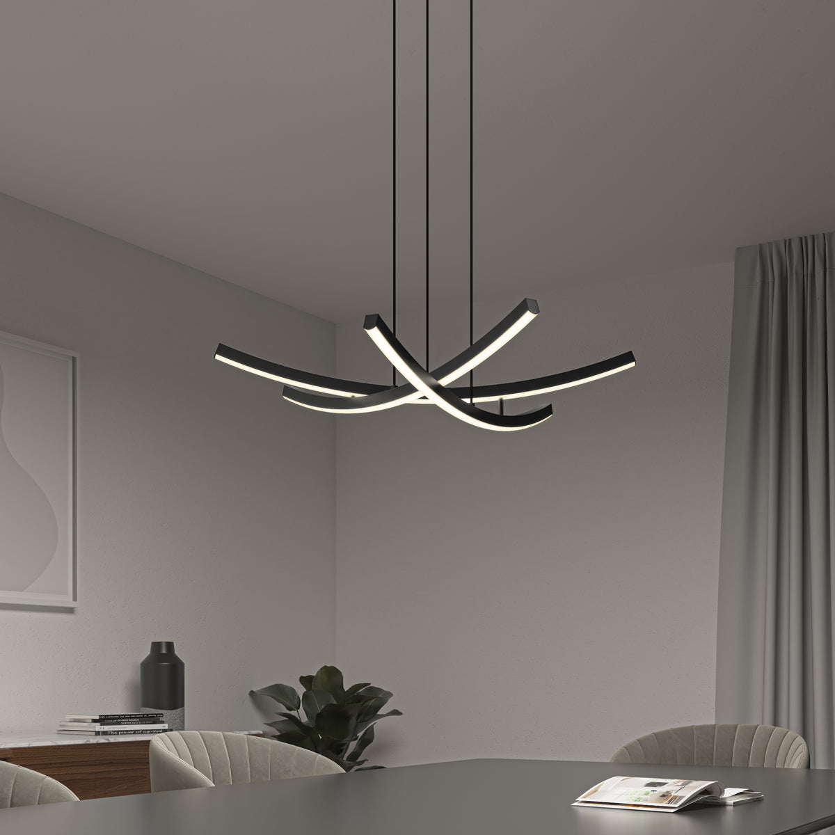 A modern dining room showcases the Orly modern LED pendant light 5 CCT by Artika with curved light strips above a dark table set with an open magazine, gray chairs, a plant, and minimal decor.