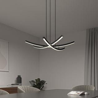 A modern dining room showcases the Orly modern LED pendant light 5 CCT by Artika with curved light strips above a dark table set with an open magazine, gray chairs, a plant, and minimal decor.