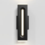 A modern black wall sconce with a vertical, recessed frosted light strip in the center, mounted on a white wall. The sconce emits soft, even illumination from the top, bottom, and center.